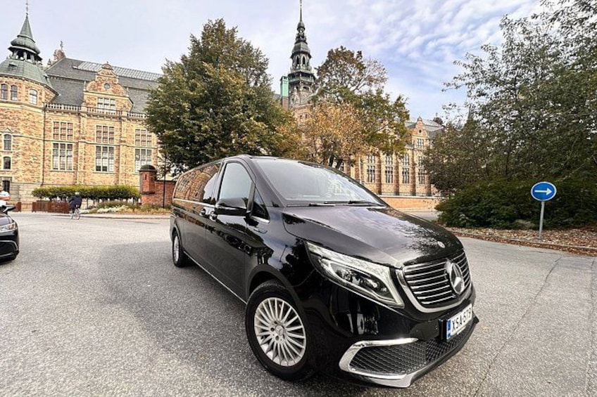 A black Mercedes-Benz SUV parked in front of a historic building with a church steeple in the background. 2