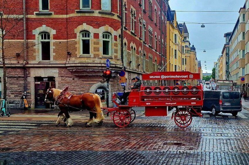 A horse-drawn carriage on a cobblestone street, a red sign with text, and historic buildings. 5