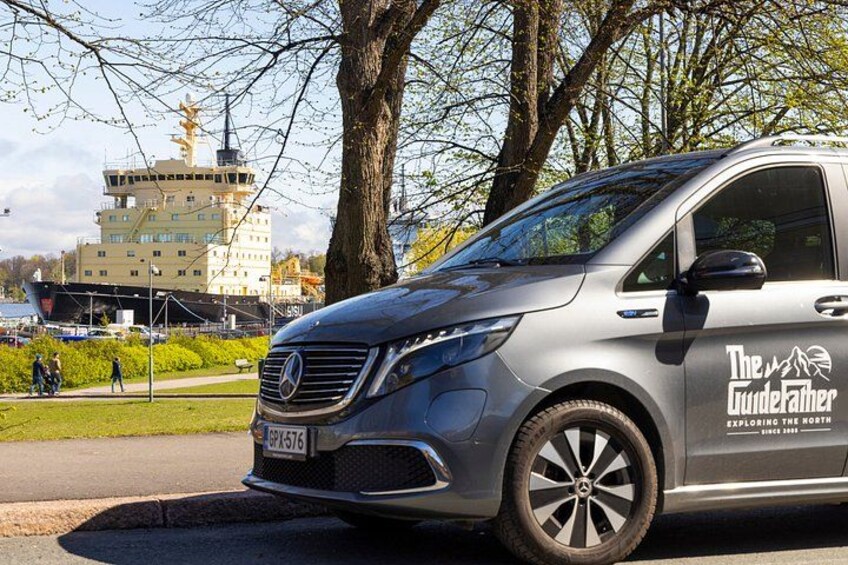 A silver Mercedes-Benz Sprinter van parked on a street with trees and a building in the background. 5