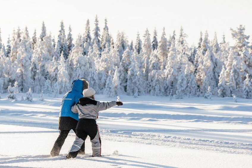 Two people in winter clothing playing in the snow with a forest in the background. 3