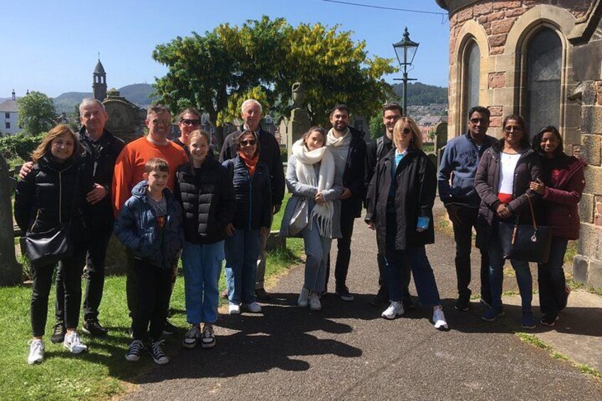 Un grupo de personas frente a un edificio de piedra con ventanas de arco y una torre con campanas. 2