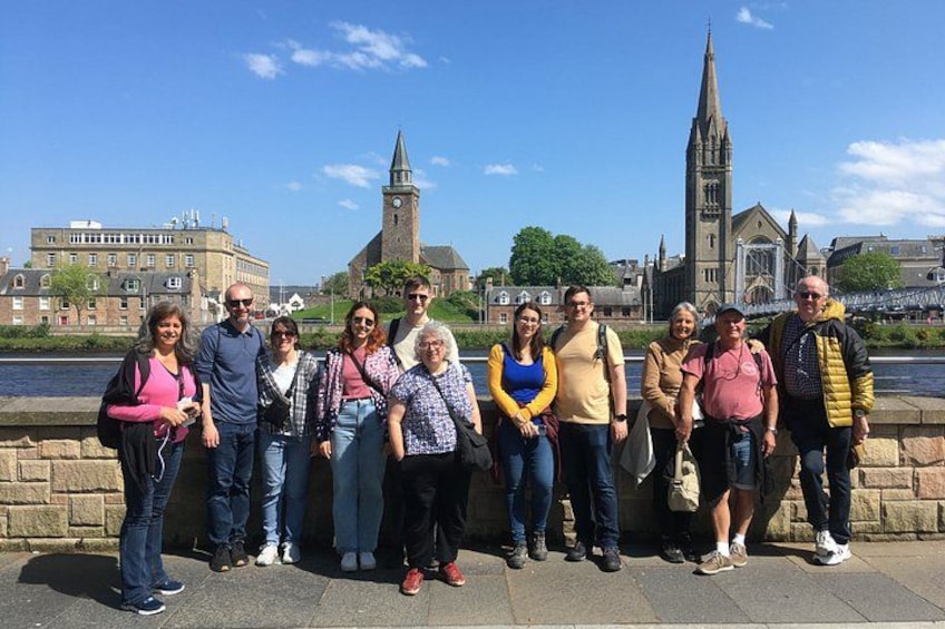 A group of people standing on a bridge with a historic building and a church in the background. 4