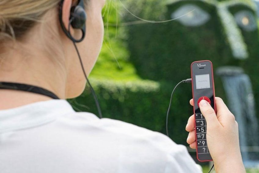 A person holding a red mobile phone with a numeric keypad. 2