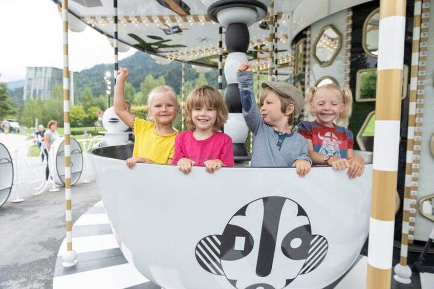 Children on a carousel with a large white seat featuring a black and white design. 3