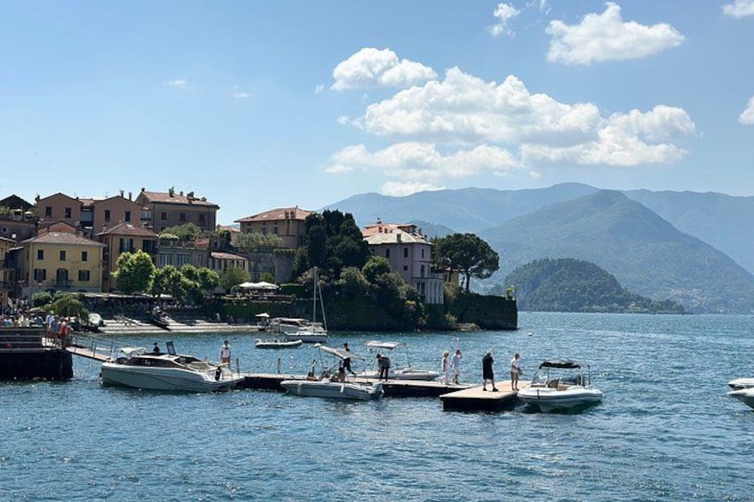 Un pueblo a orillas de un lago con barcos amarrados, edificios y montañas al fondo. 2