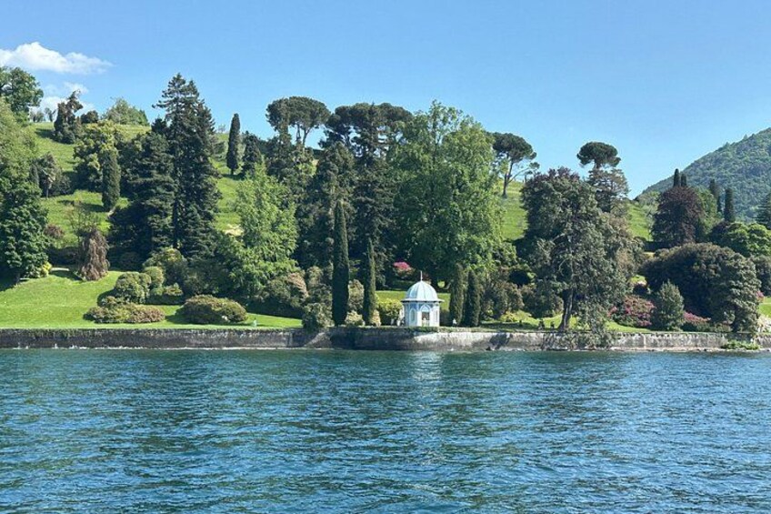 Un lago con un pabellón, abundante vegetación y colinas al fondo. 3