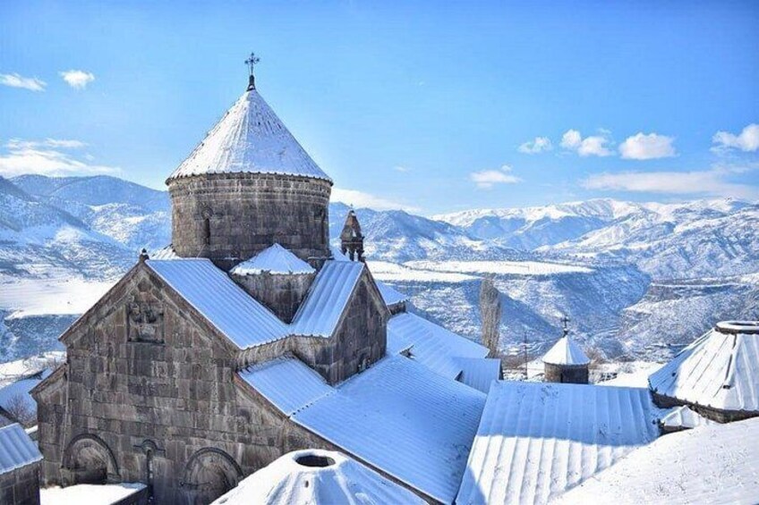 A snow-covered church with a dome and bell tower, surrounded by mountains. 5