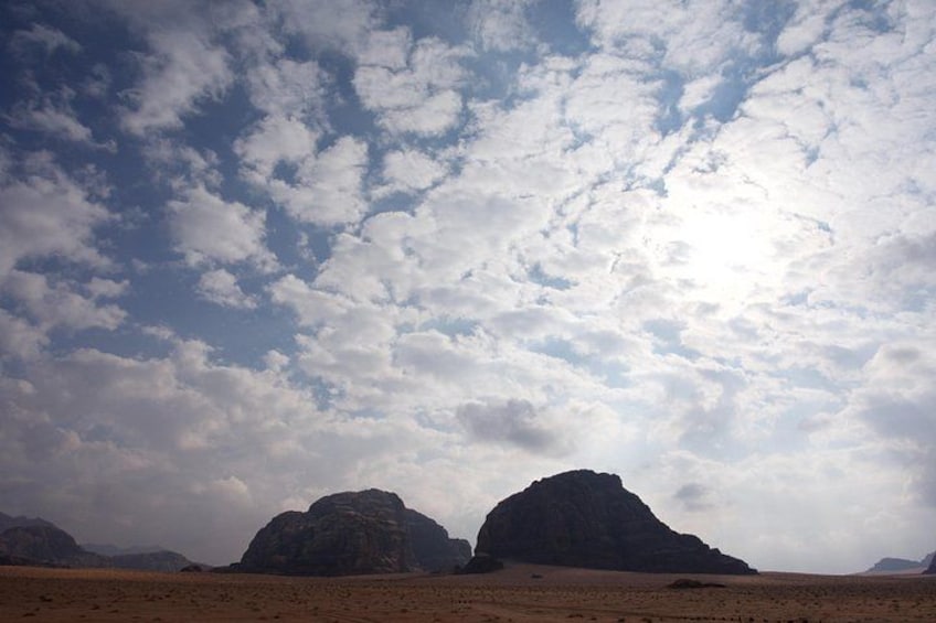 A desert landscape with rocky formations under a partly cloudy sky. 2