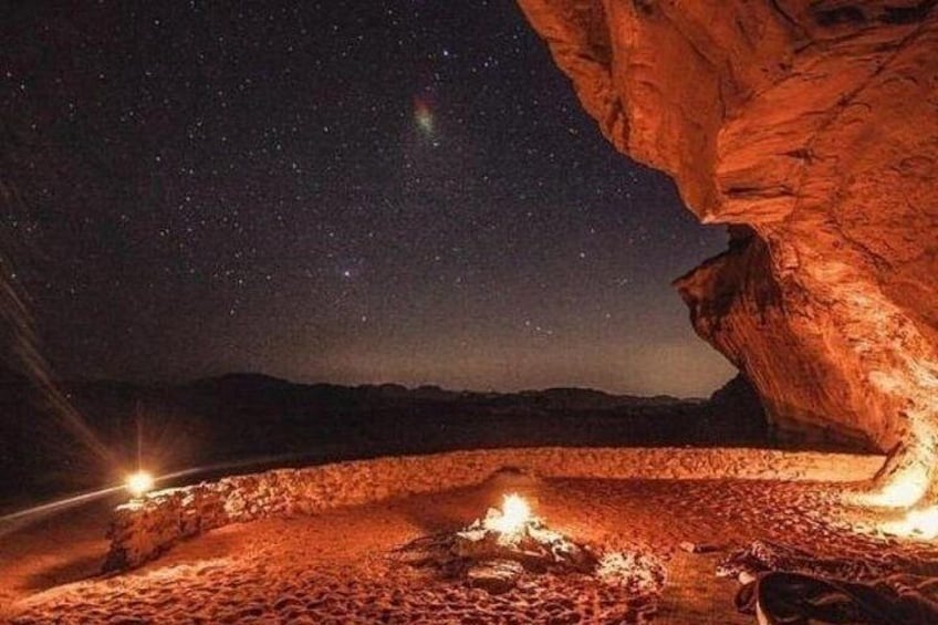 A starry night sky, a rocky landscape, and a campfire. 1