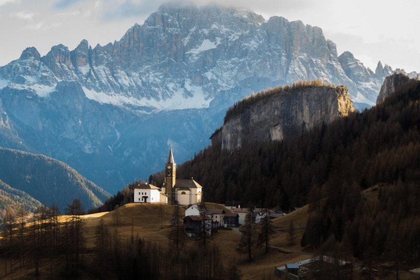 Una iglesia en una colina con montañas nevadas al fondo. 2