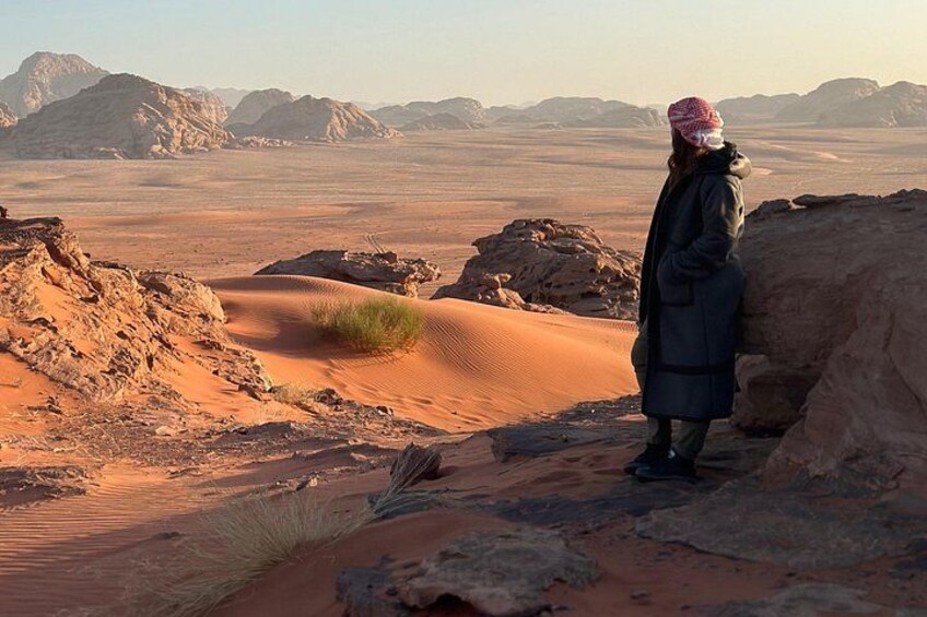 A person standing on a sand dune in a desert landscape with mountains in the background. 5