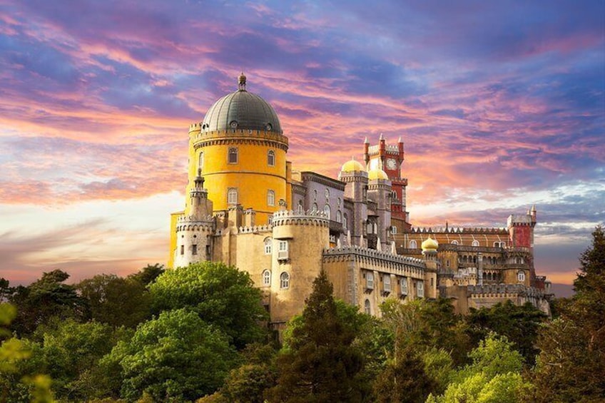 A historic castle with a yellow tower, domes, and towers against a colorful sky. 1