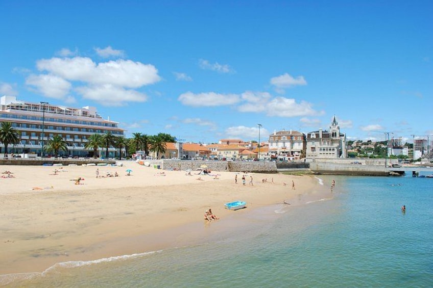 A beach with people sunbathing, a blue boat, and buildings in the background. 4