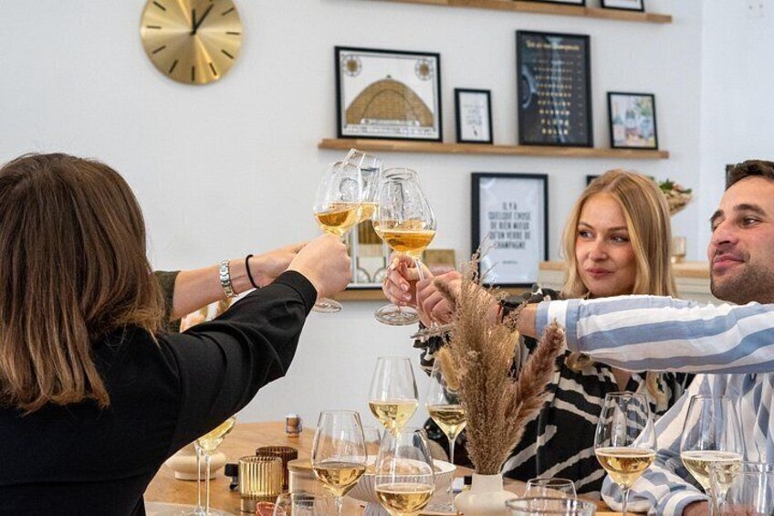 A group of people toasting with wine glasses at a table with a clock and framed pictures on the wall. 5