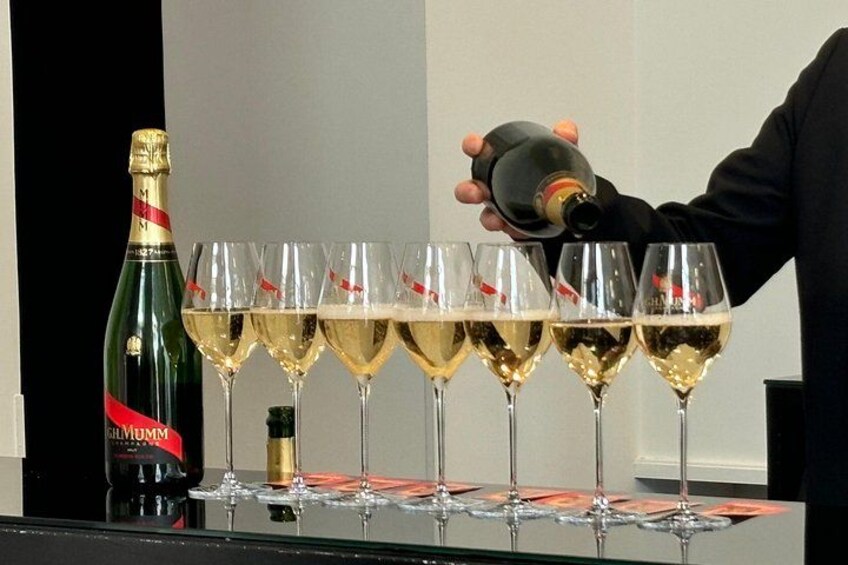 A person pouring champagne into several glasses. 3