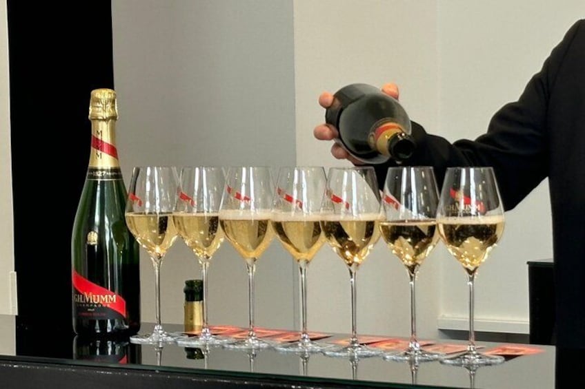 A person pouring champagne into several glasses. 3