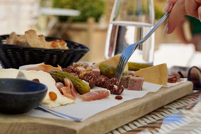 Una tabla de embutidos con diversos tipos de carne, quesos y encurtidos. 2