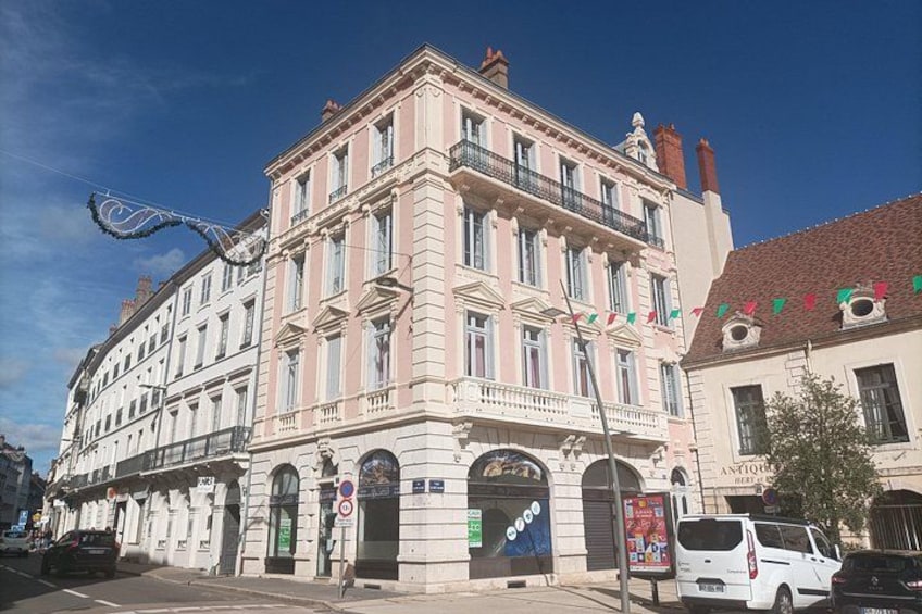 A multi-story building with classical architecture, a street sign, and a parked car. 4