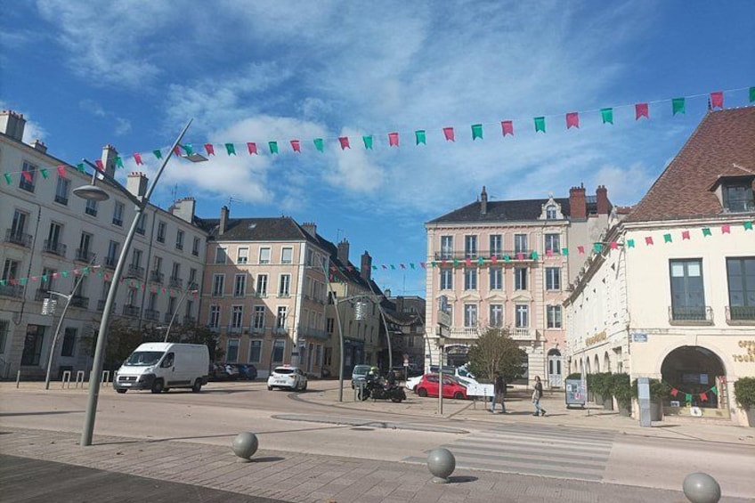 A street with buildings, a white van, cars, and decorative flags. 5