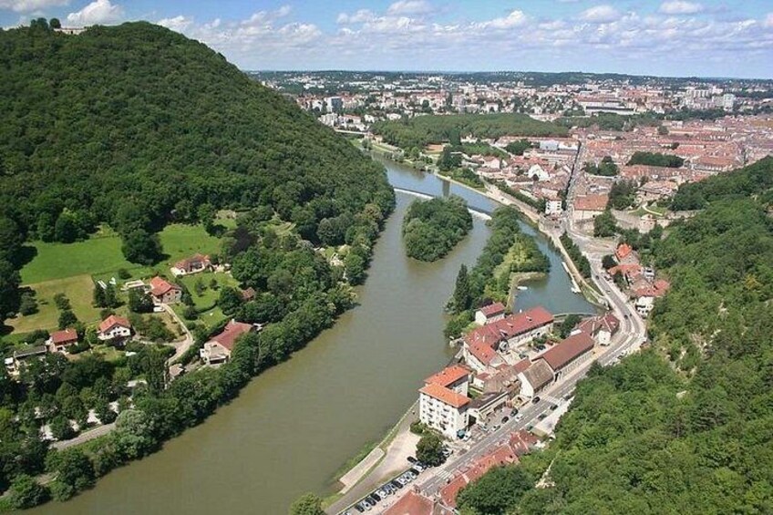 A river winding through a town with buildings and greenery. 1