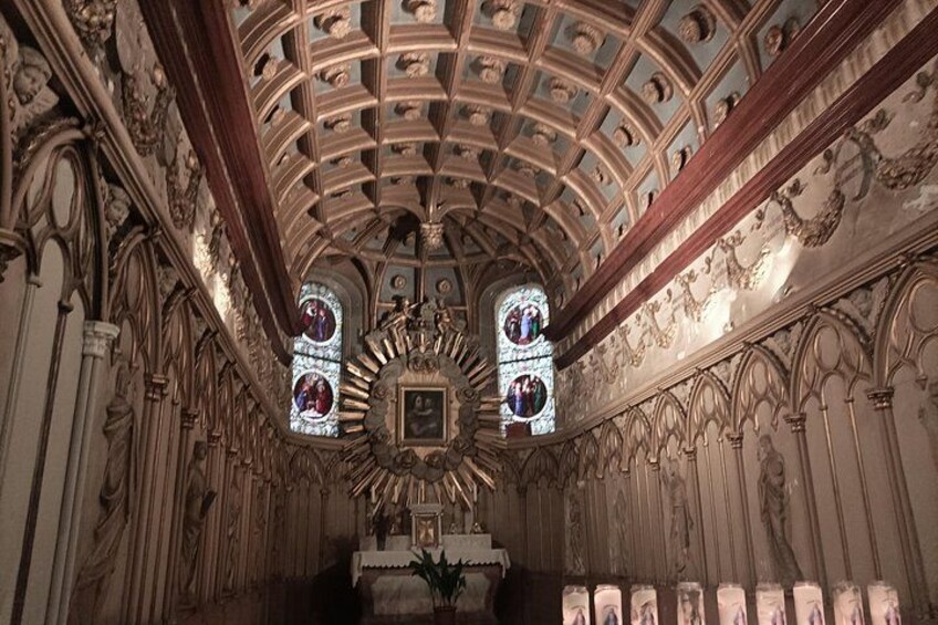 An ornate chapel interior with a vaulted ceiling, stained glass windows, and a central altar. 5