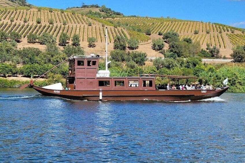 Un bote marrón con pasajeros en un río, rodeado de viñedos en terrazas. 5