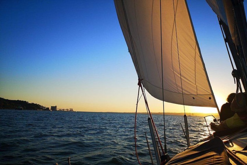 A sailboat with a white sail on a calm sea during sunset. 2