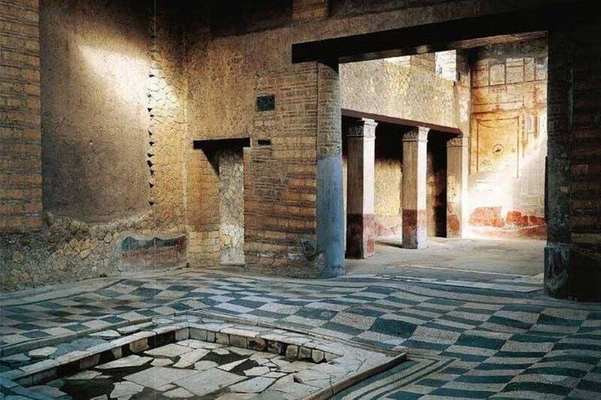 Un bâtiment ancien doté de colonnes en pierre, d’un sol à carreaux et d’un espace central ouvert. 4