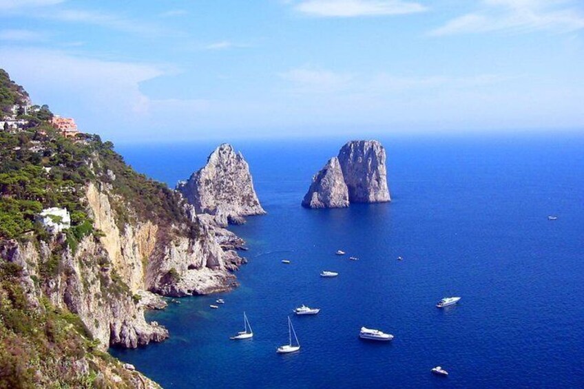 A coastal landscape with rocky cliffs and a clear blue sea. 1