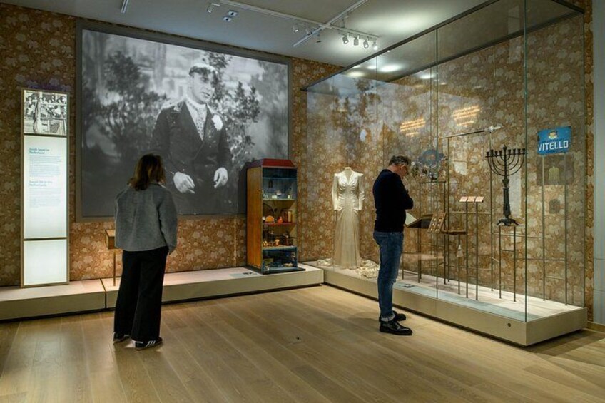 Two people observing a display with a large projection and a menorah. 1