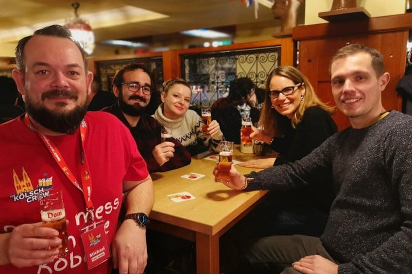 A group of people sitting at a table, holding drinks, and smiling. 3