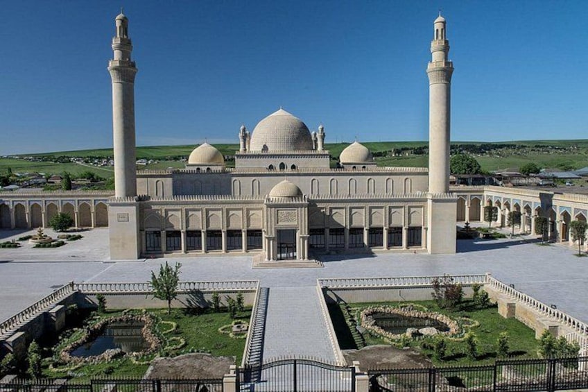 Een grote moskee met twee hoge minaretten, een centrale koepel en een binnenterrein met geometrische tuinanleg. 2