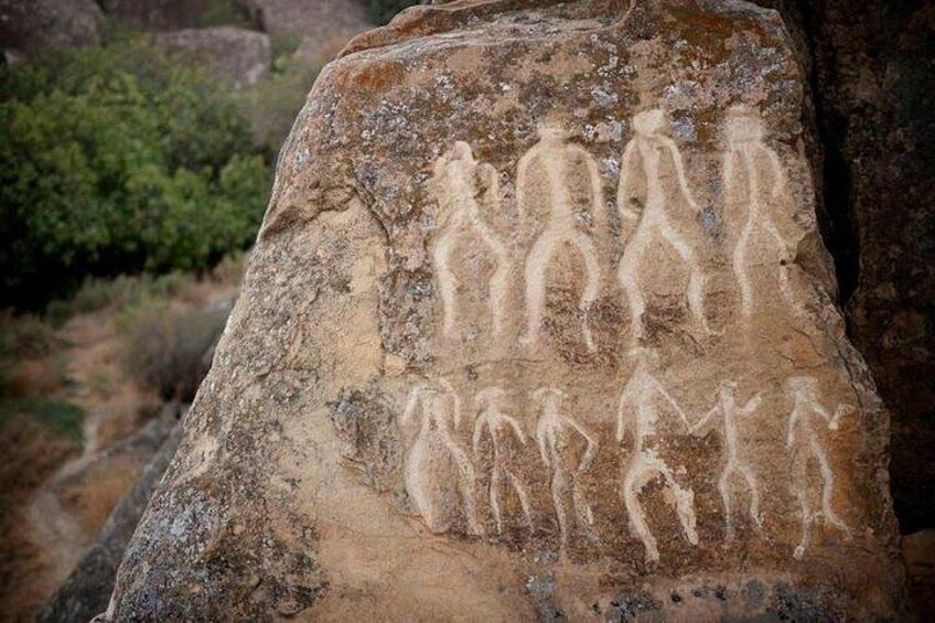 A rock with ancient human figures carved into it. 5