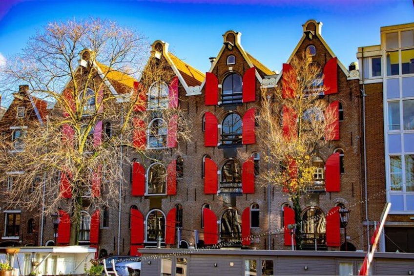 A historic building with red shutters and a tree in front. 3