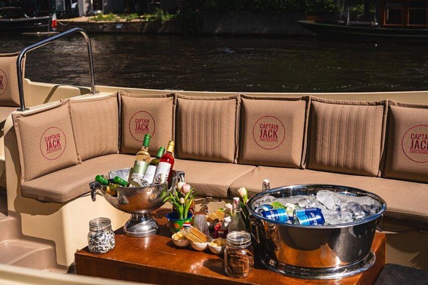 Een boot met een gewatteerde bank, een tafel met een emmer ijs, flessen en lekkernijen. 2