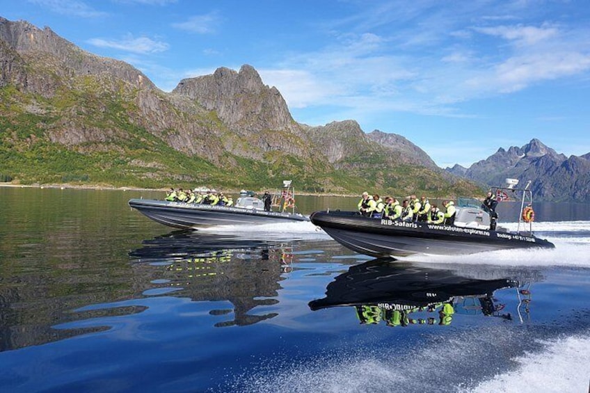 Two speedboats with passengers, a mountainous landscape, and calm water. 5