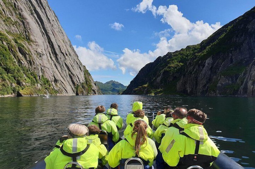 A group of people on a boat, wearing bright yellow life jackets, navigating a narrow waterway flanked by steep cliffs. 4