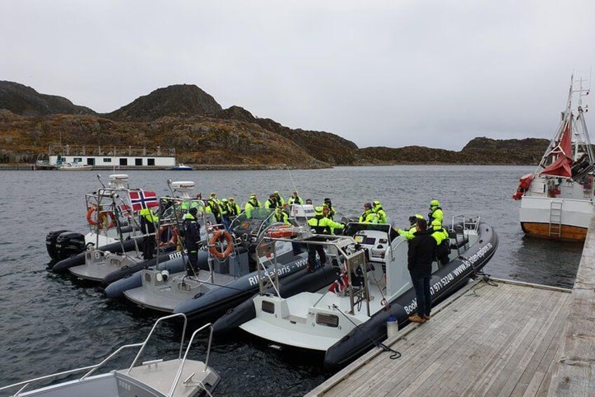 A group of people on a boat docked at a pier with a mountainous landscape in the background. 2