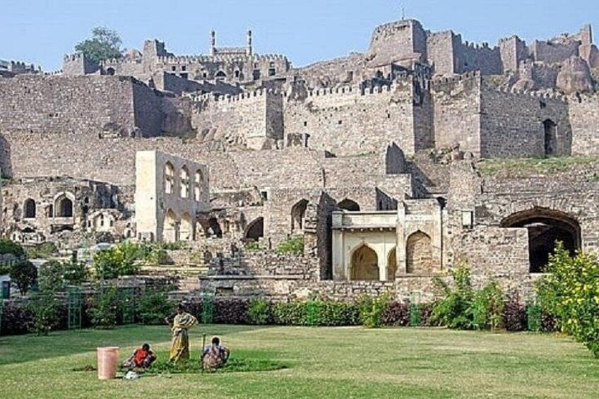 Una fortaleza histórica con ruinas y un área verde con gente. 4
