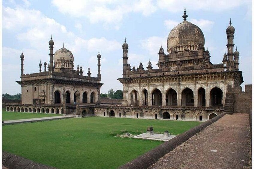 Un edificio grande e histórico con cúpulas y minaretes, rodeado por un césped verde y un sendero pavimentado. 5
