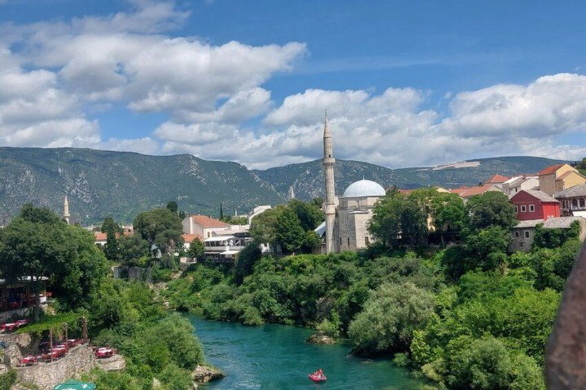A river, a mosque with a minaret, and mountains in the background. 2