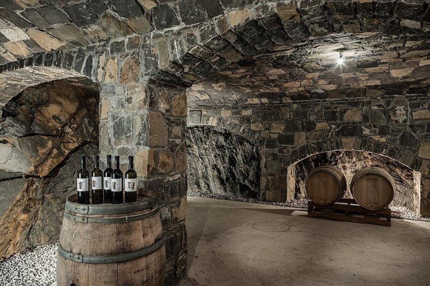 A stone cellar with wooden barrels and bottles. 3