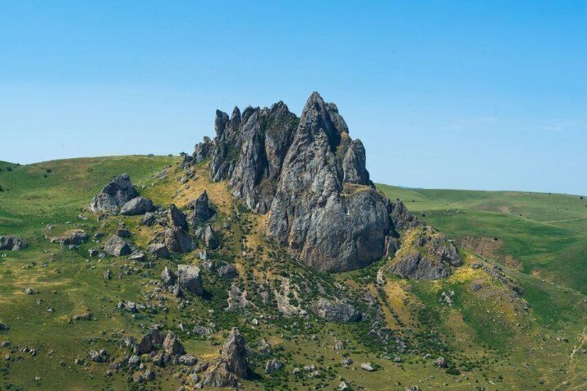 A rugged mountain peak with rocky outcrops and a grassy landscape. 4