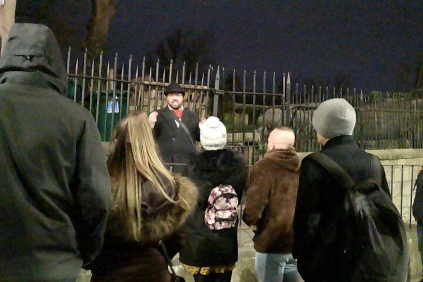 Un groupe de personnes se tient à l’extérieur, de nuit, près d’une clôture en métal. 5