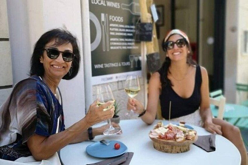 Deux personnes sont assises à une table, devant un verre de vin et un panier de nourriture. 5