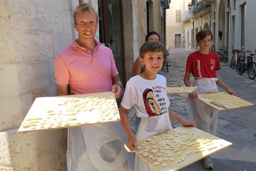 Een man en twee kinderen houden schalen met koekjes vast in een straat. 1