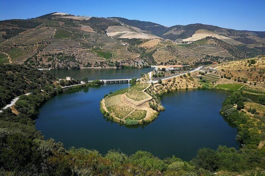 Un lago rodeado de viñedos en terrazas y un puente. 1