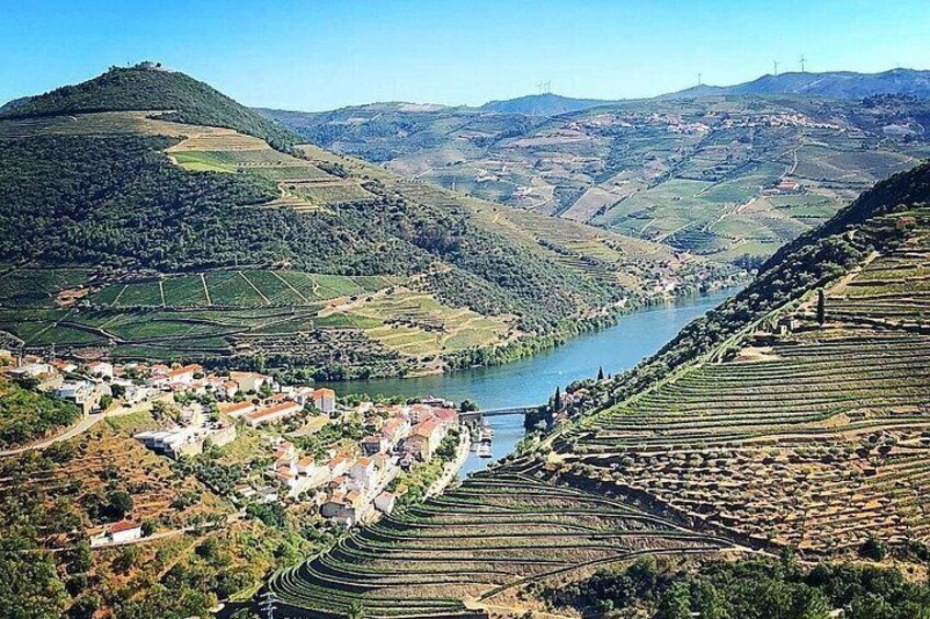 A river valley with terraced vineyards, a bridge, and a small town. 1