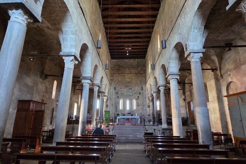 An interior of a church with rows of pews, large columns, and a wooden ceiling. 2