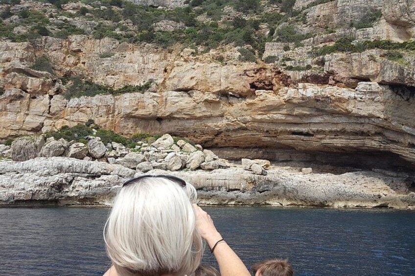 Eine felsige Küste mit einem Höhleneingang und einer Person am Wasser. 3